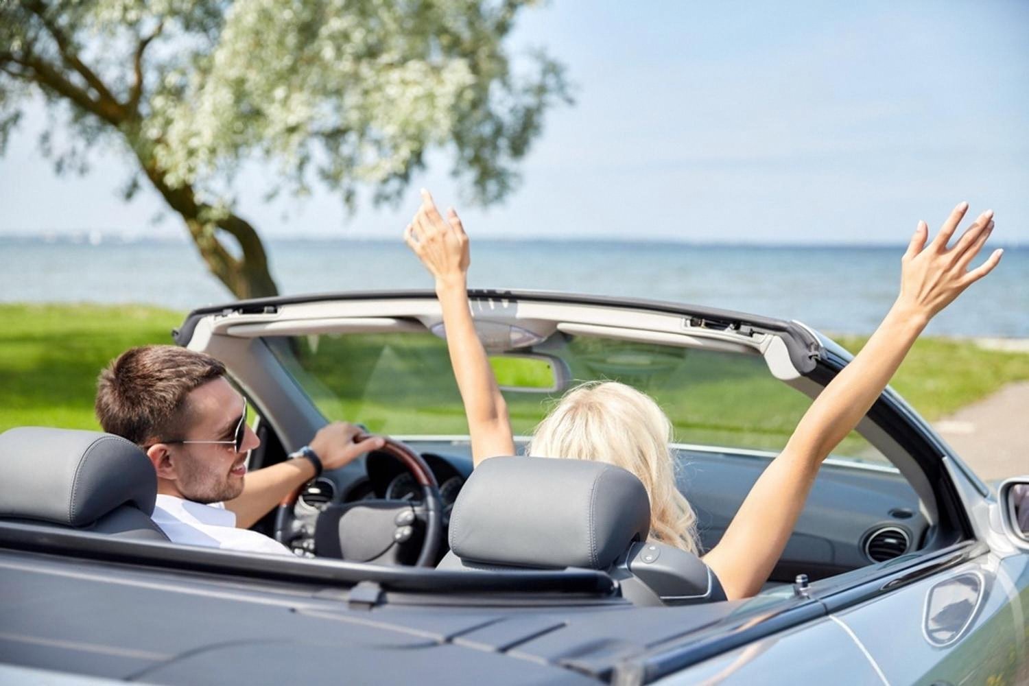 Couple in a convertible parked by the sea on a sunny day in Australia
