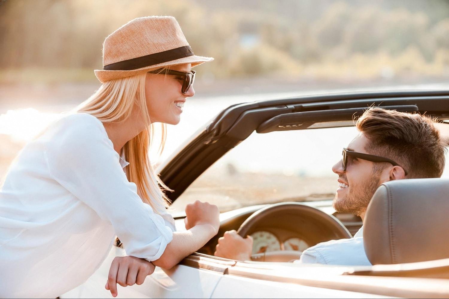 Young couple in a convertible car smiling at each other during an Australian honeymoon road trip